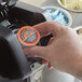 A hand holding a Caffe de Aroma Caramel Cream coffee single serve cup.