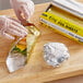 A person in plastic gloves wrapping a sandwich in Choice gold and silver interfolded foil sheets.