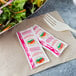 A salad with a fork and two Thousand Island dressing packets on a counter next to a bowl of salad.