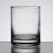 A close up of a clear Libbey shot glass with a silver rim on a table.