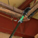 A curved pipe brush with a long handle being used to clean overhead pipes.