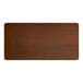 A rectangular laminated table top with a walnut finish and rounded corners.