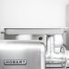 A white rectangular stainless steel Hobart meat grinder feed pan.