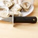 A Tablecraft Frenchman Style Oyster Knife with a black handle on a plate of oysters.