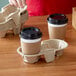 A person holding two coffee cups in an EcoChoice Pulp Fiber cup carrier.