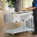 A stainless steel natural gas-powered hot food table with three open wells for holding food pans.