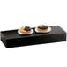 Two Cal-Mil Midnight Plate Risers with fruit tarts on a black rectangular surface.