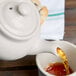 A person pouring tea into a Hall China ivory teapot.