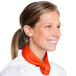 A woman in a white chef's coat wearing an orange Intedge neckerchief.