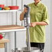 A woman in a chef's uniform using a Robot Coupe commercial immersion blender in a professional kitchen.