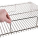 A hand holding the Optimal Automatics Party Que Grill grate with a metal handle.