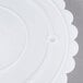 A white plastic Wilton cake separator plate with a scalloped edge.