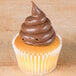 A cupcake with brown frosting piped on top using an Ateco plain piping tip.