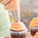 A large plain piping tip being used to frost a cupcake.