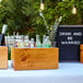 A Cal-Mil vintage wood ice housing on a table with bottles of champagne inside.