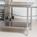 An Advance Tabco stainless steel work table with undershelf and wheels.