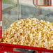 A red Carnival King container with a large amount of popcorn.