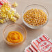 A table with bowls of popcorn and yellow liquid.