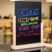 An American Metalcraft natural wood-finish menu board on a counter with colorful writing that says "Check out more delicious dishes"