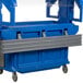 A grey plastic tray rail for a blue plastic container on a table.