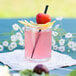 a glass of pink liquid with a strawberry on top