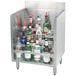 A stainless steel Advance Tabco liquor display shelf holding clear and green bottles of alcohol.