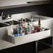 A stainless steel double tier speed rail on a counter with bottles of alcohol in it.