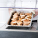 A chef using an Advance Tabco buffet hot food table to serve food on a tray.