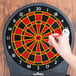 A hand holding a dart in an Arachnid CricketPro dart board.