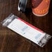 A coffee cup with a Double Serving Hot Beverage Condiment Kit on a table.