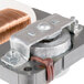 A close-up of a metal part with a copper coil and copper wire.