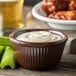 A white bowl of chocolate ramekin with white sauce inside and celery sticks.