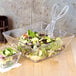 A salad in a clear square bowl.