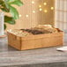 An American Metalcraft rectangular poplar wood basket filled with bread on a table in a bakery display.