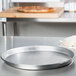 An American Metalcraft aluminum deep dish pizza pan on a counter with a pizza in it.