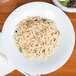 A CAC Super Bright White Coupe porcelain bowl filled with noodles on a table.