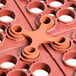 A red plastic floor mat connector with four holes.