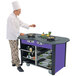 A chef cooking food in a pan on a Lakeside stainless steel cooking cart.