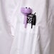 A close up of a purple pen in the pocket of a white Chef Revival executive chef coat with black piping.