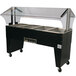 An Advance Tabco stainless steel electric hot food table with an open base and clear cover on wheels.