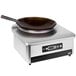 A Vollrath countertop induction wok range with a carbon steel wok pan.