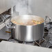 A Vollrath Miramar casserole pan with soup on a stove.