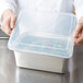 A chef holding a Vollrath clear polypropylene container with salad in it.