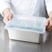 A chef holding a Vollrath clear plastic container with a snap-on lid filled with food.