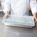 A chef holding a Vollrath clear plastic container of food.