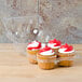 A clear plastic InnoPak container holding three cupcakes with red and white frosting.