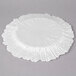 A white Charge It by Jay glass charger plate with a scalloped edge and a circular design.