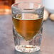 A Libbey fluted shot glass filled with brown liquid.