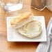 An Acopa bright white square porcelain plate with a biscuit and butter on it.