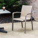 A Grosfillex Sunset Cognac outdoor stacking armchair on a patio.